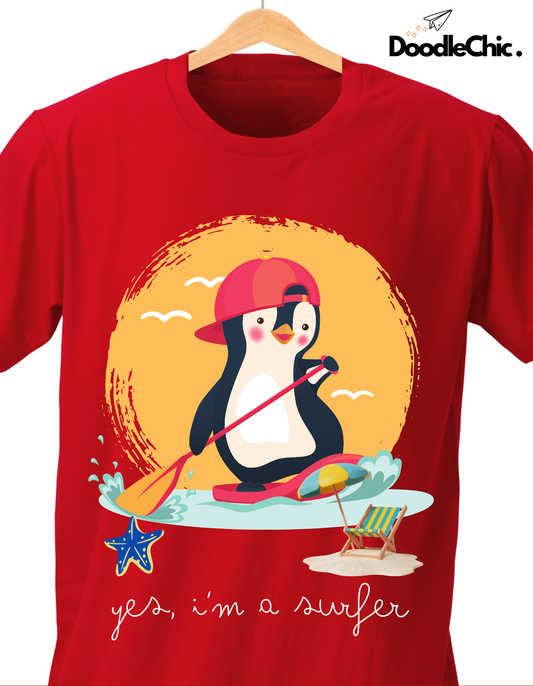 Close-up of Penguin Surfer by DoodleChic - 100% Organic Cotton Red Kids T-shirt showing playful penguin graphic with paddleboard, starfish, and beach chair.