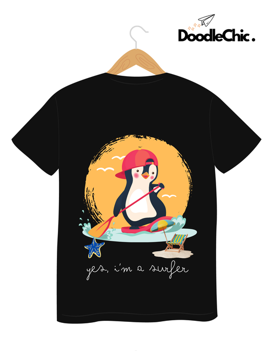Penguin Surfer - Doodlechic 100% Organic Cotton Black Kids T-shirt on hanger, showcasing a playful penguin surfing design with beach elements.
