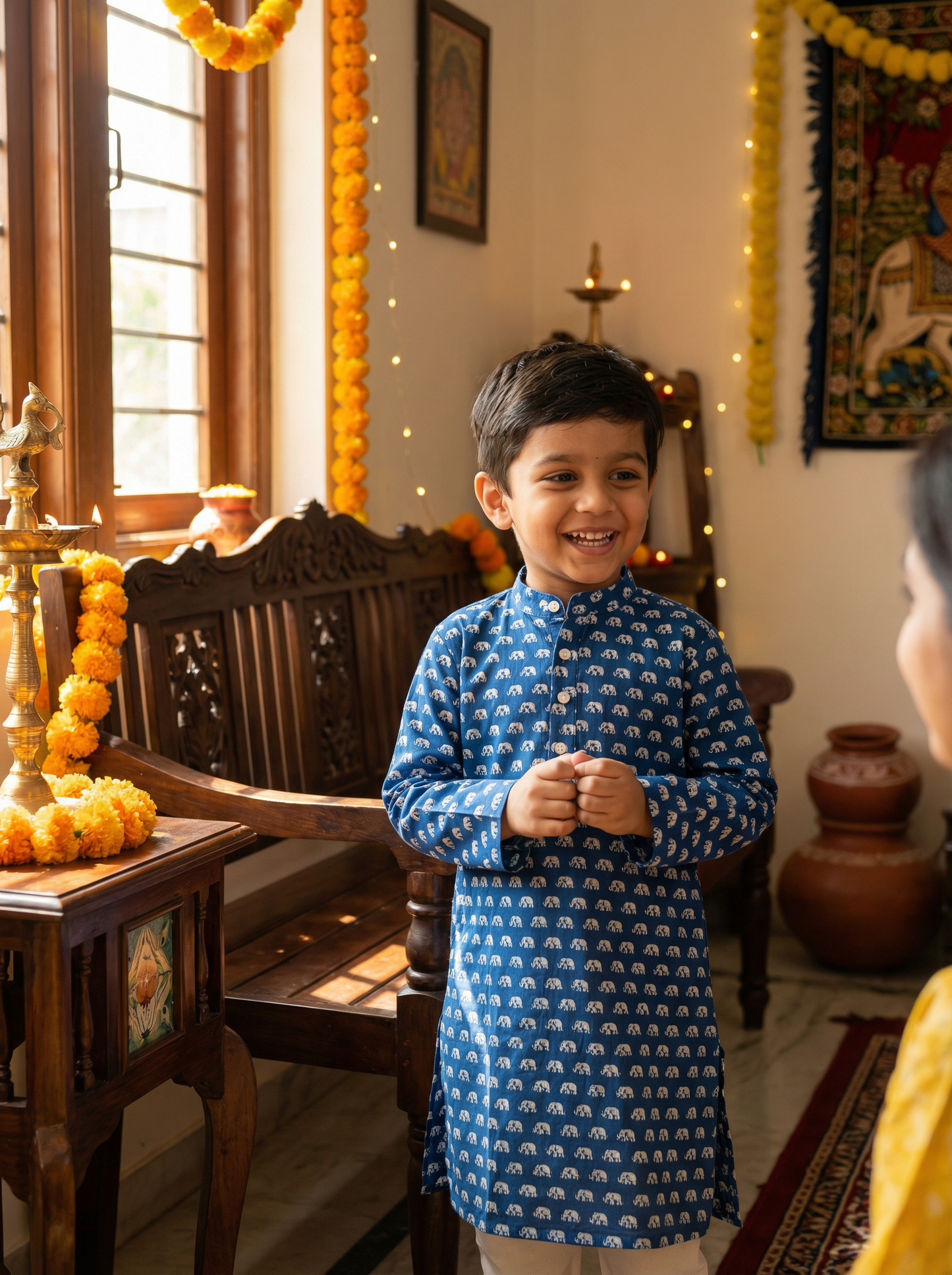 Child in a blue kurta standing in a decorated room with festive elements.